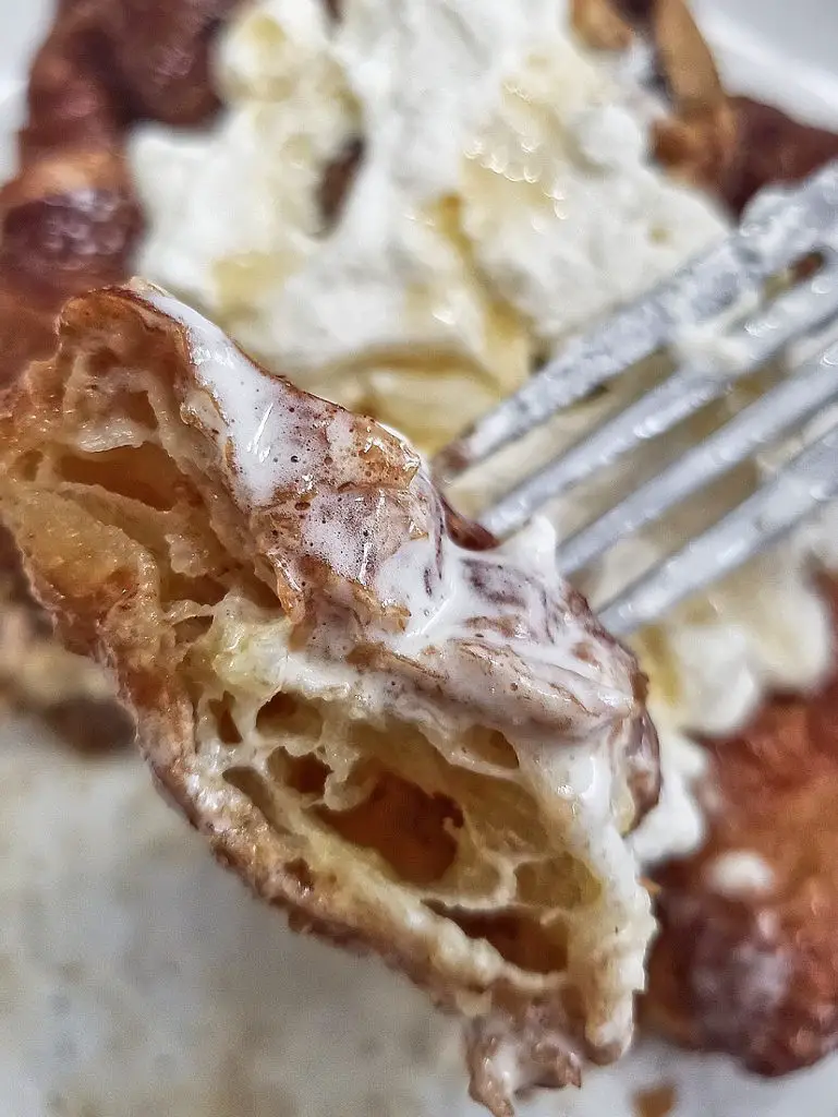 bite of french toast croissant with fresh whipped cream and maple syrup