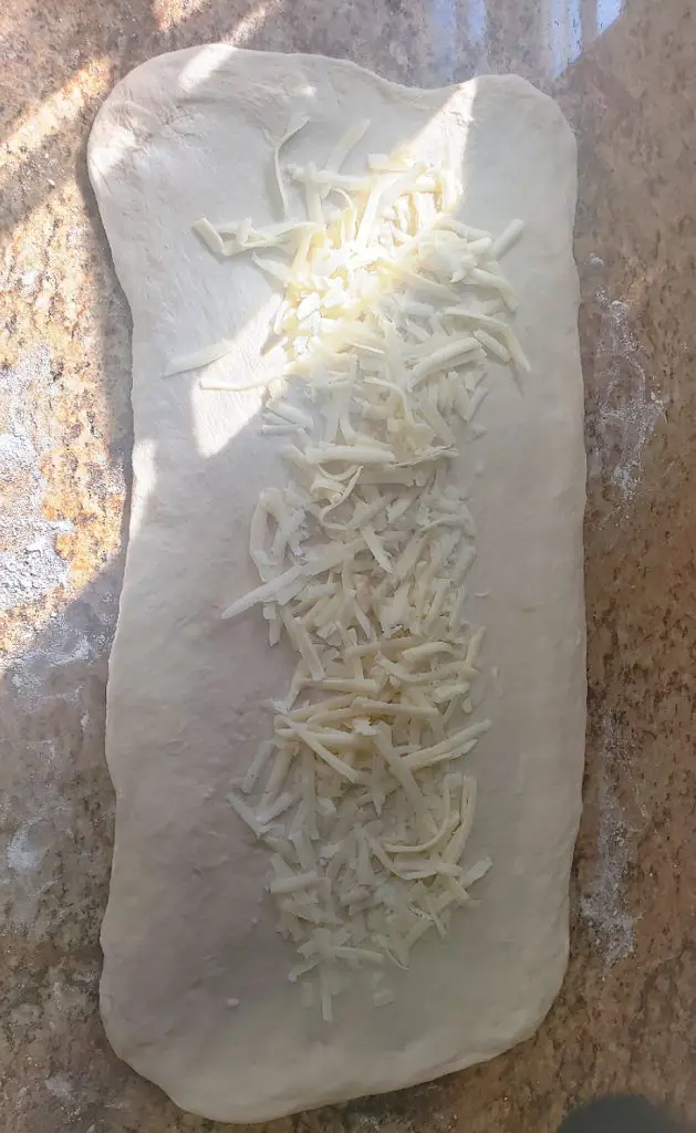 layer of shredded cheese on rectangular shape of dough