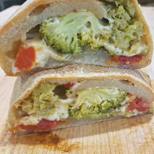 two stromboli slices with broccoli tomatoes and cheese