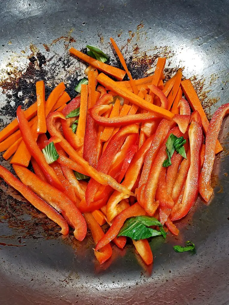 saute carrots and red peppers in wok