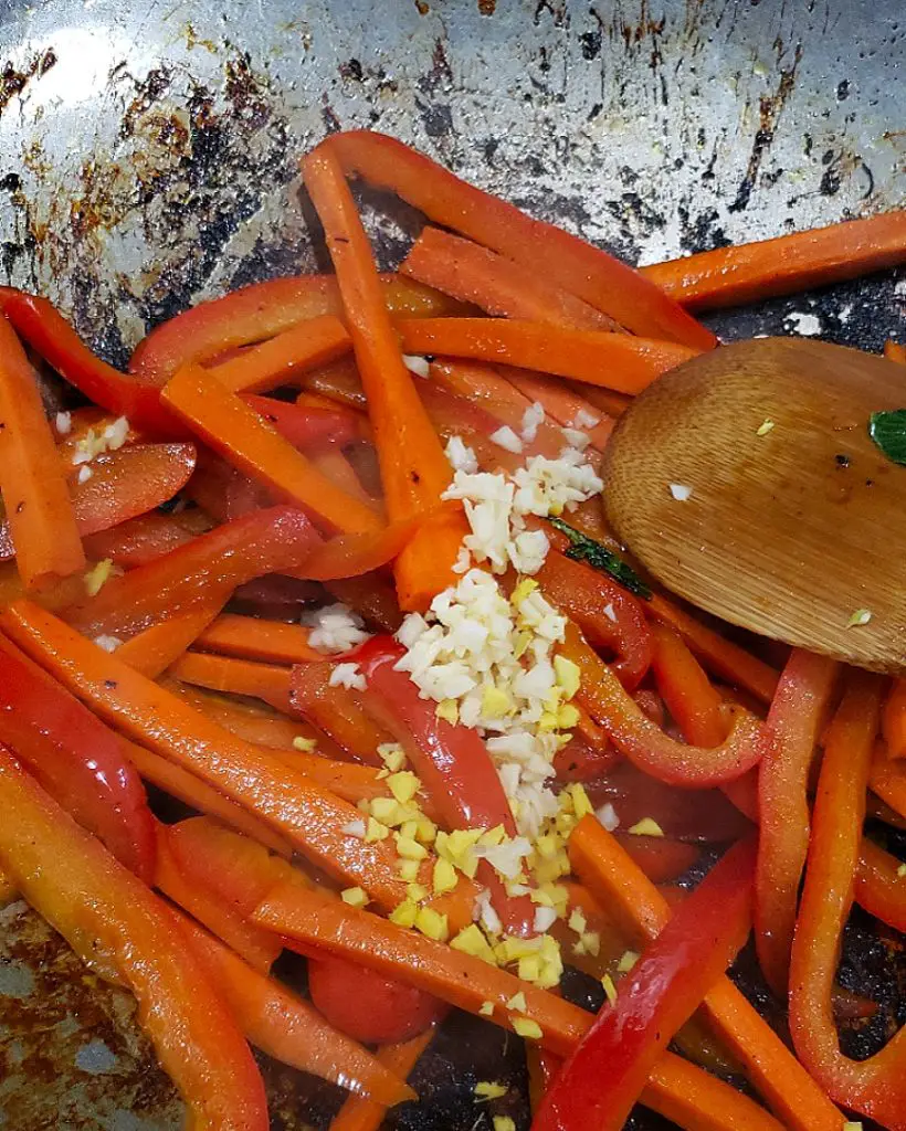 add minced garlic and ginger to vegetables in wok
