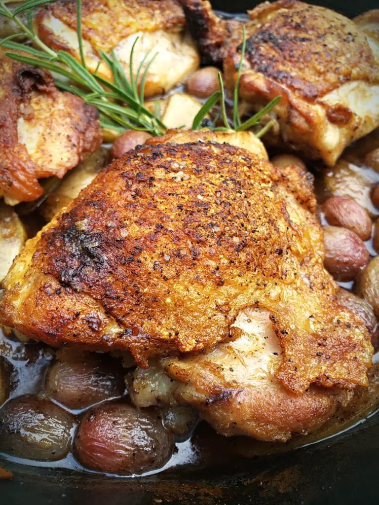 image of crispy Chicken Thighs in a cast iron skillet with Apple, Grape and Sage pan Sauce