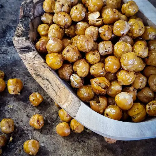 up close side angle image of wooden bowl of crisp chickpeas