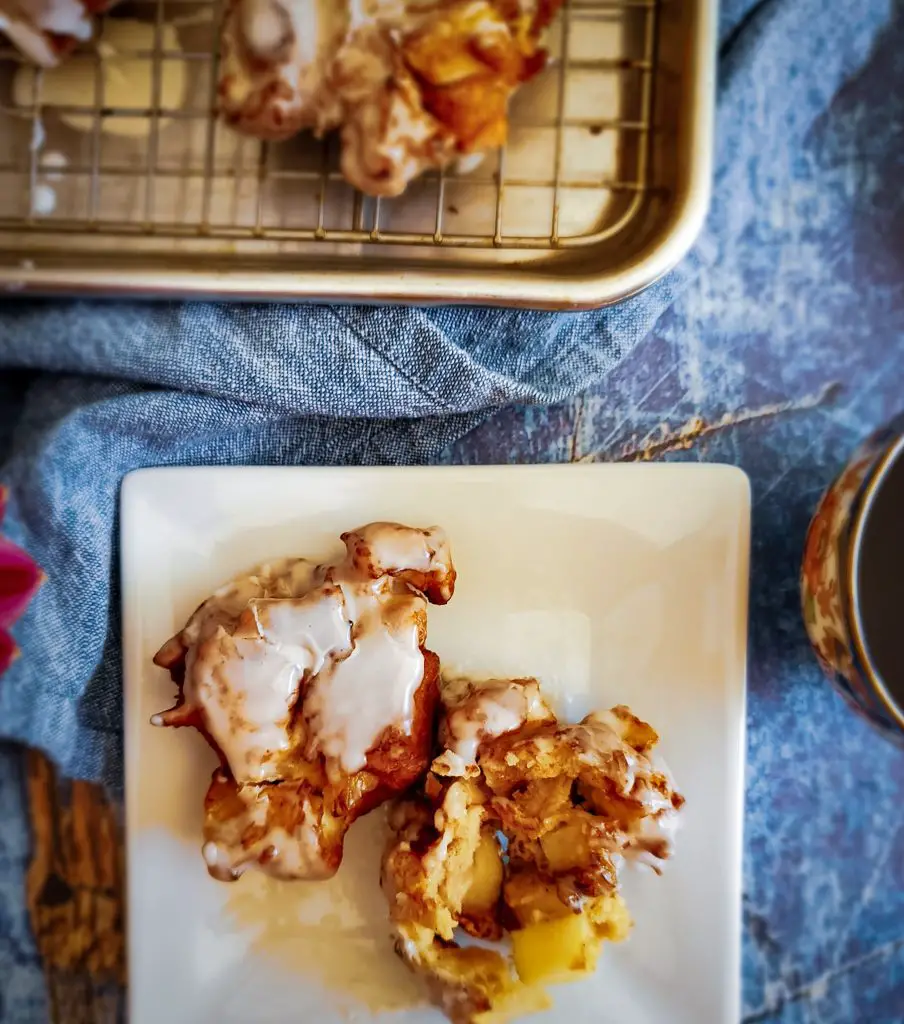 image of CHAI-SPICED APPLE FRITTERS WITH VANILLA GLAZE on plate with cup of coffee
