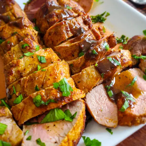 Side angel view of sliced pork tenderloin on white plate