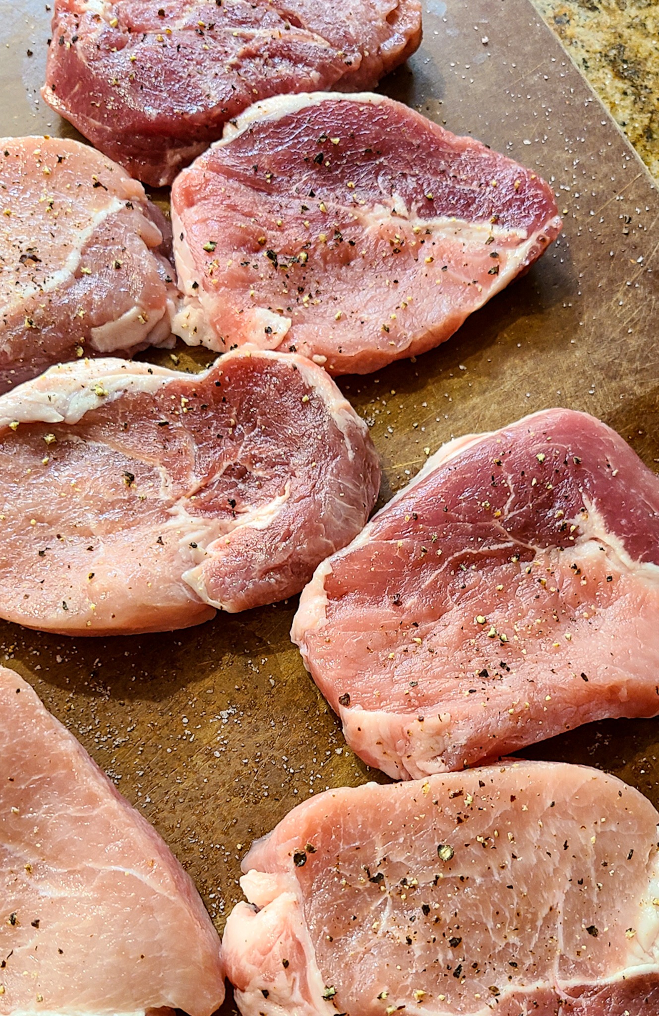 raw seasoned pork chops on cutting board