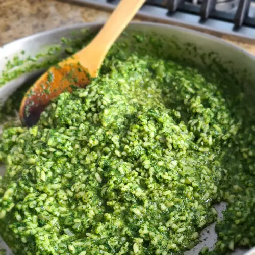 Vibrant green spinach risotto in skillet with wooden spoon
