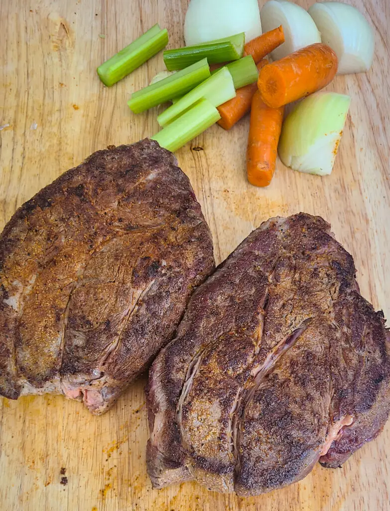 image of seared beef chuck roast on cutting board next to vegetables