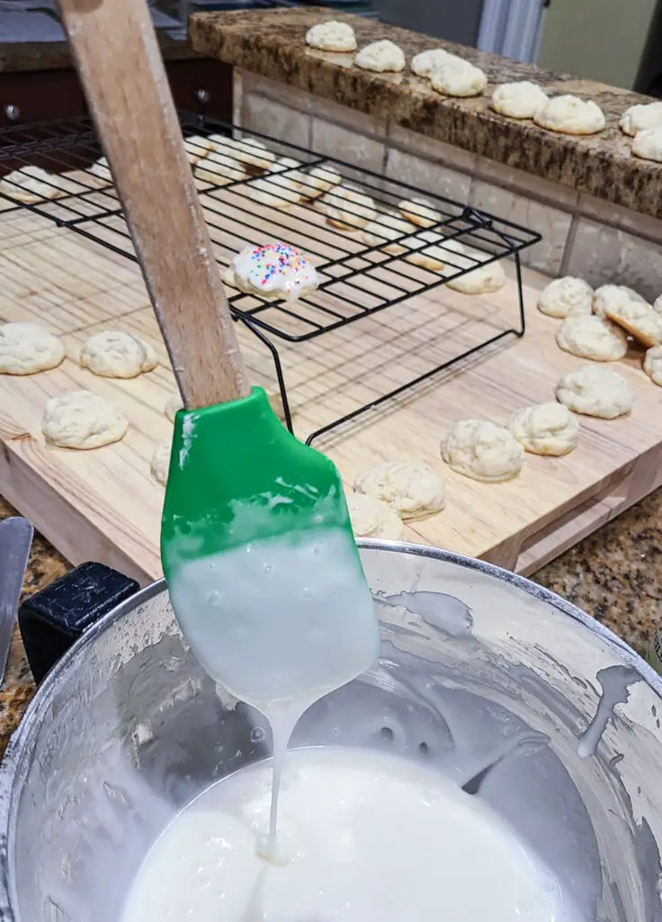 image of lemon icing in mixing bowl with spatula dipped in icing to show the desired thickness of cookie icing