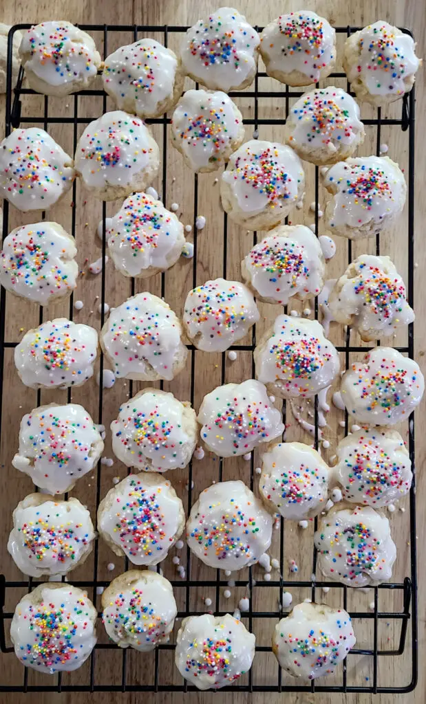 over head image of Italian lemon ricotta cookies with icing a sprinkles set on a cooling rack to dry