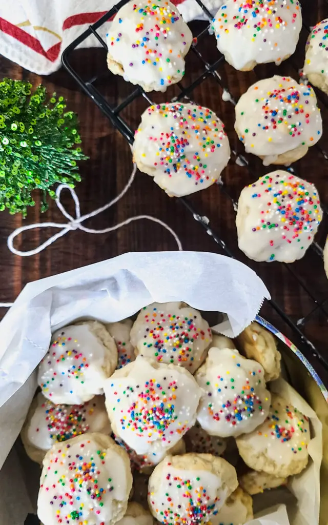 decorative image of a christmas cookie tin filled with lemon ricotta cookies and a bow of bakers twine laying next to it