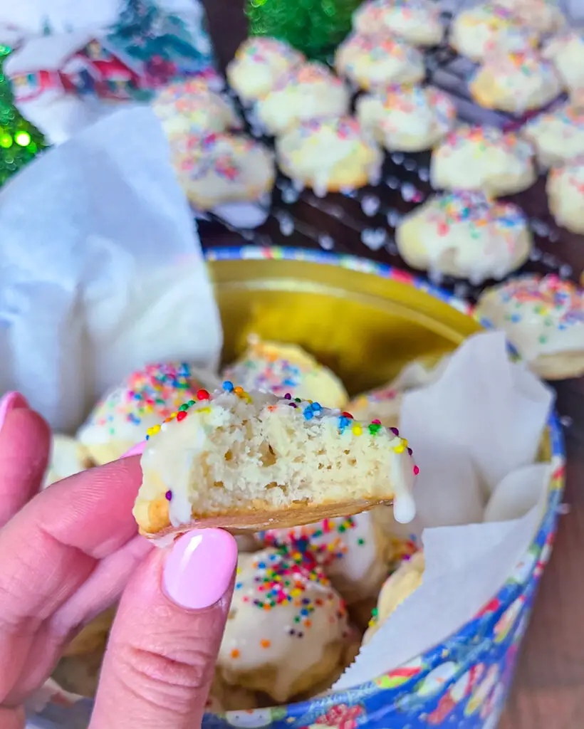 image of hand holding a bitten italian lemon ricotta cookie with intent to show the texture of inside of cookie